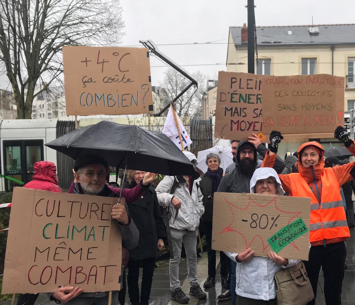 Manifestation avec pancartes "+4°C ça coûte combien ?" "Plein·e d'énergie mais sans moyen" "Transition énergétique : des objectifs sans moyens, ça sert à rien !" "Culture, climat, même combat" "-80% pour la transition écologique"